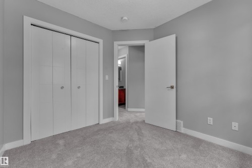 Neutral gray wall paint with white trim, gray carpet flooring, and white bi-fold closet doors - 12221 117 Avenue Nw, Edmonton, AB - Indoor Photo Showing Other Room