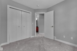 Neutral gray wall paint with white trim, gray carpet flooring, and white bi-fold closet doors - 