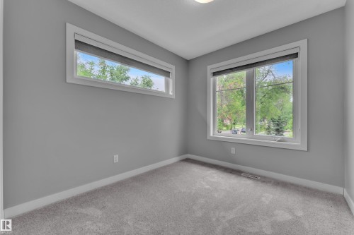 Room featuring a large picture window, a high horizontal window, light gray walls, white trim, and gray carpeting - 12221 117 Avenue Nw, Edmonton, AB - Indoor Photo Showing Other Room