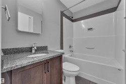 Bathroom featuring a dark wood-finish vanity with a speckled countertop, an undermount sink, and a chrome faucet - 