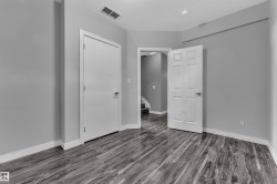 Room featuring wood-finish flooring, light gray walls, white baseboards, and two white doors - 