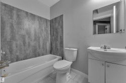 Bathroom featuring a white bathtub, toilet, and vanity with an integrated sink - 