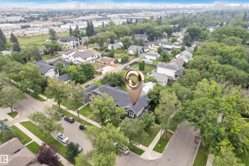 Residential property featuring a dark grey exterior and a dark roof, surrounded by mature trees and paved streets - 12221 117 Avenue Nw, Edmonton, AB - Outdoor With View
