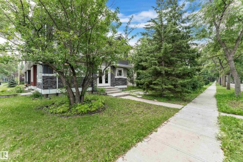 Exterior featuring stone facade detailing, white trim windows, and a prominent front entrance with double white doors - 12221 117 Avenue Nw, Edmonton, AB - Outdoor