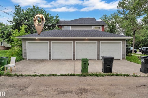 Four-car garage with individual white garage doors and a paved concrete driveway - 12221 117 Avenue Nw, Edmonton, AB - Outdoor
