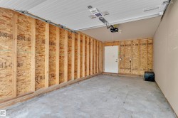 Garage interior featuring exposed wood framing and concrete flooring - 