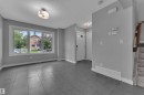 Spacious entry area featuring large format tile flooring, a prominent three-panel window, a white paneled entry door with frosted glass inserts, and a carpeted staircase with a wood handrail - 12221 117 Avenue Nw, Edmonton, AB  - Indoor Photo Showing Other Room 