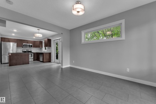 Open-concept living area featuring gray plank tile flooring, a horizontal window, and recessed lighting - 12221 117 Avenue Nw, Edmonton, AB - Indoor Photo Showing Kitchen