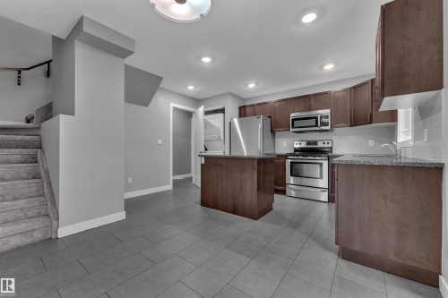 Kitchen featuring dark wood-finish cabinetry, stainless steel appliances, and a central island - 12221 117 Avenue Nw, Edmonton, AB - Indoor Photo Showing Kitchen