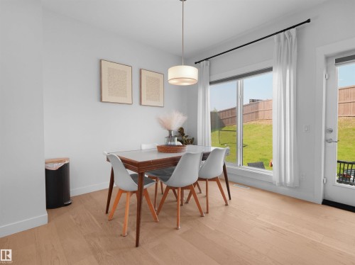 Bright dining area with wood-finish flooring, a contemporary drum pendant light, and a large sliding glass door opening to a private fenced yard - 22650 99A Avenue Nw, Edmonton, AB - Indoor Photo Showing Dining Room