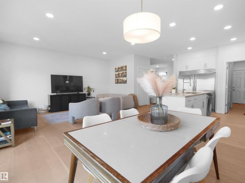 Open-concept living space featuring wood-finish flooring, recessed lighting, a modern drum pendant light, and a kitchen with stainless steel appliances - 22650 99A Avenue Nw, Edmonton, AB - Indoor Photo Showing Dining Room