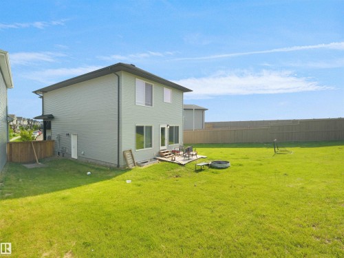Expansive green space featuring a wooden privacy fence, a ground-level patio, and a walk-out basement entrance - 22650 99A Avenue Nw, Edmonton, AB - Outdoor
