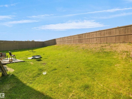 Expansive backyard featuring a large green lawn, a wood fence, and a patio area - 22650 99A Avenue Nw, Edmonton, AB - Outdoor