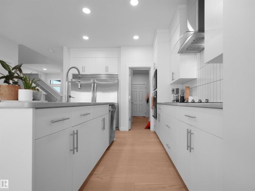 Modern kitchen featuring a stainless steel refrigerator, pull-down faucet, and sleek white cabinetry with bar pulls - 22650 99A Avenue Nw, Edmonton, AB - Indoor Photo Showing Kitchen With Upgraded Kitchen