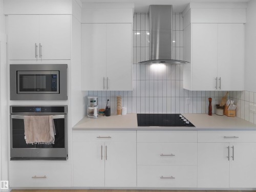 Modern kitchen featuring white flat-panel cabinetry, a stainless steel wall oven and microwave, a built-in cooktop, a stainless steel range hood, and a white vertical subway tile backsplash - 22650 99A Avenue Nw, Edmonton, AB - Indoor Photo Showing Kitchen