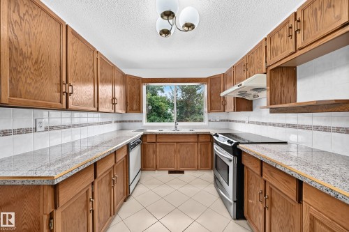 Galley kitchen with wood-finish cabinetry, tile flooring, stone-finish countertop - 17915 99A Avenue Nw, Edmonton, AB 