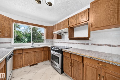 Kitchen featuring wood cabinetry, white tile backsplash, and a window above the sink - 17915 99A Avenue Nw, Edmonton, AB 