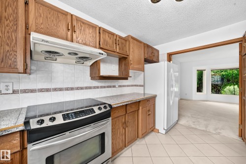 Kitchen featuring tile flooring, wood-finish cabinetry, a stainless steel range - 17915 99A Avenue Nw, Edmonton, AB 