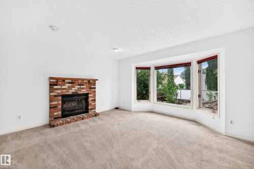 Brick fireplace with a wood mantel, bay windows looking out to pond - 17915 99A Avenue Nw, Edmonton, AB 