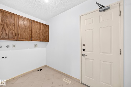 Tile flooring, built-in wooden cabinetry, white walls, and a paneled entry door - 17915 99A Avenue Nw, Edmonton, AB 