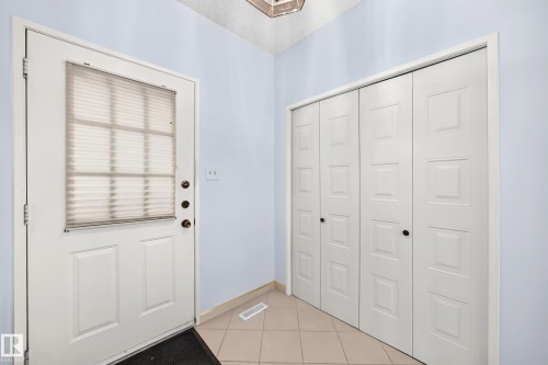 Entryway featuring a paneled door with integrated blind, bi-fold closet doors, and tile flooring - 17915 99A Avenue Nw, Edmonton, AB 