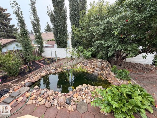 Water feature with a rock-lined pond, stone waterfall, and surrounding landscaping - 17915 99A Avenue Nw, Edmonton, AB 