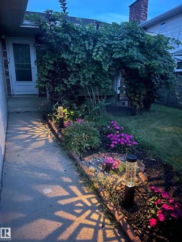 Manicured garden beds featuring varied plantings and decorative path lighting - 17915 99A Avenue Nw, Edmonton, AB 