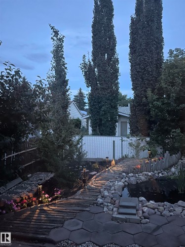 Landscaped backyard featuring a pond, stone rockery, and a wood-slat walkway - 17915 99A Avenue Nw, Edmonton, AB 