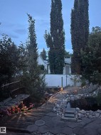 Landscaped backyard featuring a pond, stone rockery, and a wood-slat walkway - 