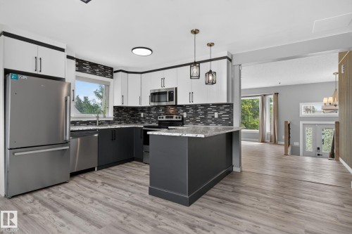 Modern kitchen featuring two-tone cabinetry, stainless steel appliances, a mosaic tile backsplash, and a central island with a stone-finish countertop - 9530 174 Avenue Nw, Edmonton, AB - Indoor Photo Showing Kitchen With Upgraded Kitchen