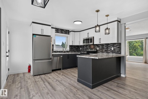 Contemporary kitchen featuring two-tone cabinetry, stainless steel appliances, a tiled backsplash, and an island with a countertop - 9530 174 Avenue Nw, Edmonton, AB - Indoor Photo Showing Kitchen With Upgraded Kitchen