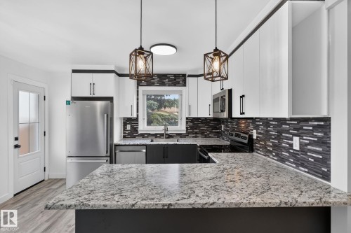Kitchen featuring white upper cabinetry, dark lower cabinetry, and stainless steel appliances - 9530 174 Avenue Nw, Edmonton, AB - Indoor Photo Showing Kitchen With Upgraded Kitchen