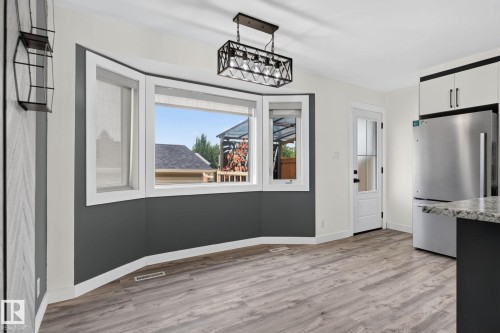 Bay window with white trim and dark accent wall, wood-finish flooring, and a modern rectangular chandelier - 9530 174 Avenue Nw, Edmonton, AB - Indoor