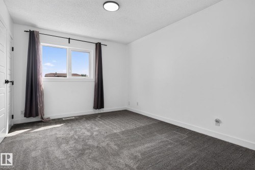 Bright room featuring white walls, gray carpeting, a large window, and a flush-mount ceiling light - 9530 174 Avenue Nw, Edmonton, AB - Indoor Photo Showing Other Room