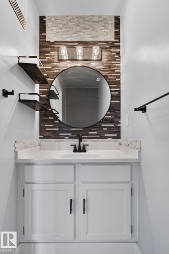 White vanity with shaker-style cabinetry, a white countertop, and an undermount sink with a matte black faucet - 9530 174 Avenue Nw, Edmonton, AB - Indoor