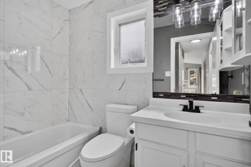 Bathroom featuring a white vanity with an integrated sink, matte black faucet, and a large mirror with a decorative tile border - 9530 174 Avenue Nw, Edmonton, AB - Indoor Photo Showing Bathroom