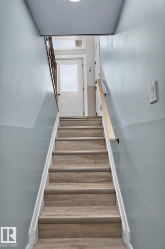 Stairwell featuring wood-finish treads, a light wood handrail, and light blue painted walls - 9530 174 Avenue Nw, Edmonton, AB - Indoor Photo Showing Other Room