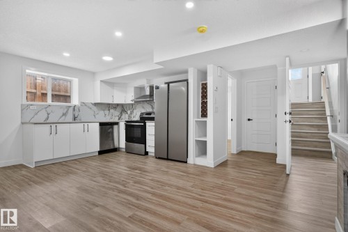 Contemporary kitchen featuring white cabinetry, stainless steel appliances, and a marble-patterned backsplash - 9530 174 Avenue Nw, Edmonton, AB - Indoor Photo Showing Kitchen