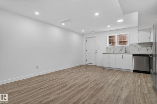 Open-concept room featuring wood-finish flooring, recessed lighting, and a modern kitchen area - 9530 174 Avenue Nw, Edmonton, AB - Indoor