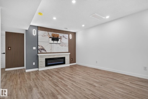 Accent wall featuring a built-in electric fireplace with a stone-finish surround and mantel - 9530 174 Avenue Nw, Edmonton, AB - Indoor With Fireplace