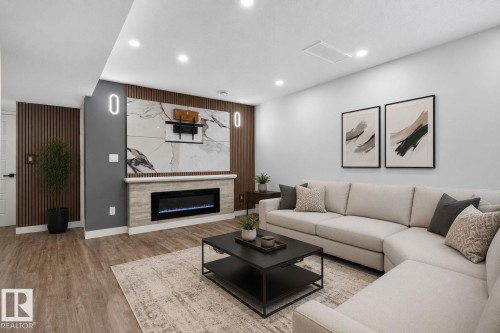Spacious living area featuring wood-finish flooring, recessed lighting, and a contemporary fireplace with a stone-finish mantel - 9530 174 Avenue Nw, Edmonton, AB - Indoor Photo Showing Living Room With Fireplace