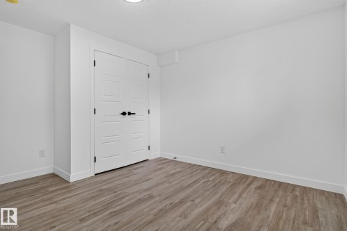 White interior door set with matte black hardware, framed by neutral walls and wood-finish flooring - 9530 174 Avenue Nw, Edmonton, AB - Indoor Photo Showing Other Room