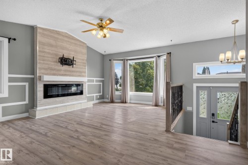Spacious living area featuring plank wood-finish flooring, a contemporary linear fireplace with a textured surround, and a bay window - 9530 174 Avenue Nw, Edmonton, AB - Indoor Photo Showing Living Room With Fireplace