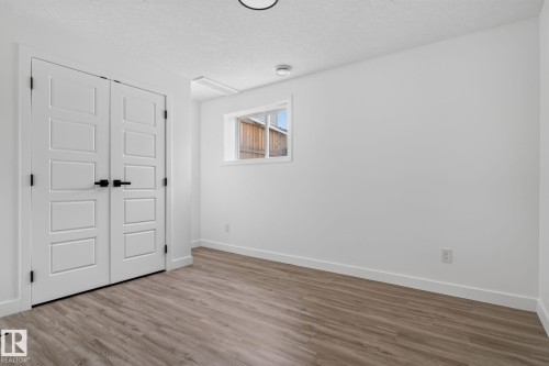 Room featuring wood-finish flooring, crisp white walls, and a window with white trim - 9530 174 Avenue Nw, Edmonton, AB - Indoor Photo Showing Other Room