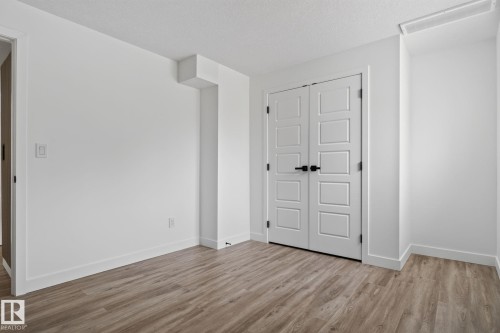 Light wood-finish flooring complements white walls and modern trim - 9530 174 Avenue Nw, Edmonton, AB - Indoor Photo Showing Other Room