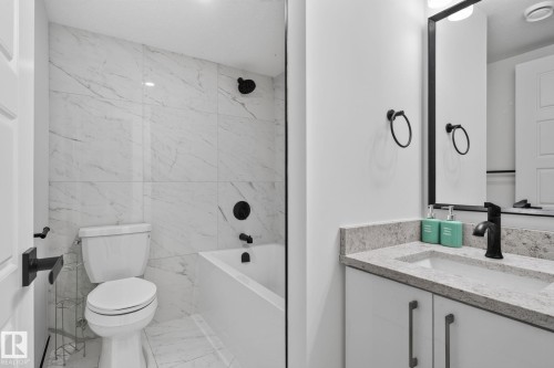 Bathroom featuring a white subway tile shower surround with black fixtures, a soaking tub, and a toilet - 9530 174 Avenue Nw, Edmonton, AB - Indoor Photo Showing Bathroom
