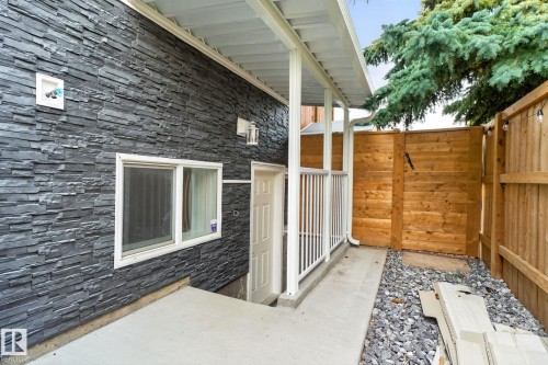 Exterior featuring dark stacked stone cladding, white framed window, and a covered entry with white railings - 9530 174 Avenue Nw, Edmonton, AB - Outdoor With Exterior