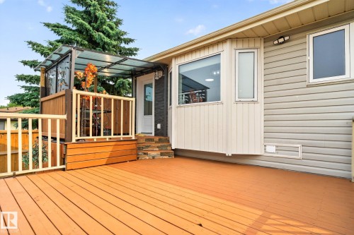 Expansive wooden deck with a covered outdoor seating area, multiple windows, and light grey siding - 9530 174 Avenue Nw, Edmonton, AB - Outdoor With Deck Patio Veranda With Exterior