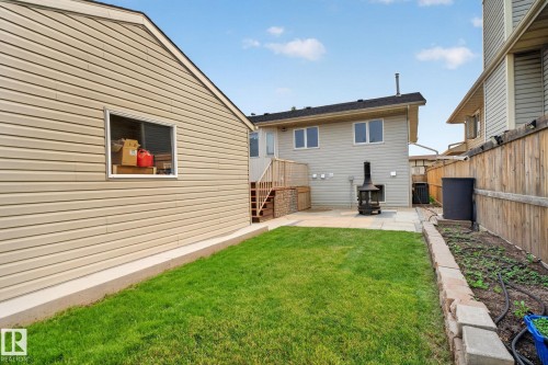 Expansive backyard featuring a stone patio, manicured lawn, and raised garden bed with stone retaining wall - 9530 174 Avenue Nw, Edmonton, AB - Outdoor With Exterior