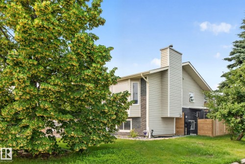 Multi-level residence featuring light-toned siding, a prominent chimney, and a partial stone facade - 9530 174 Avenue Nw, Edmonton, AB - Outdoor